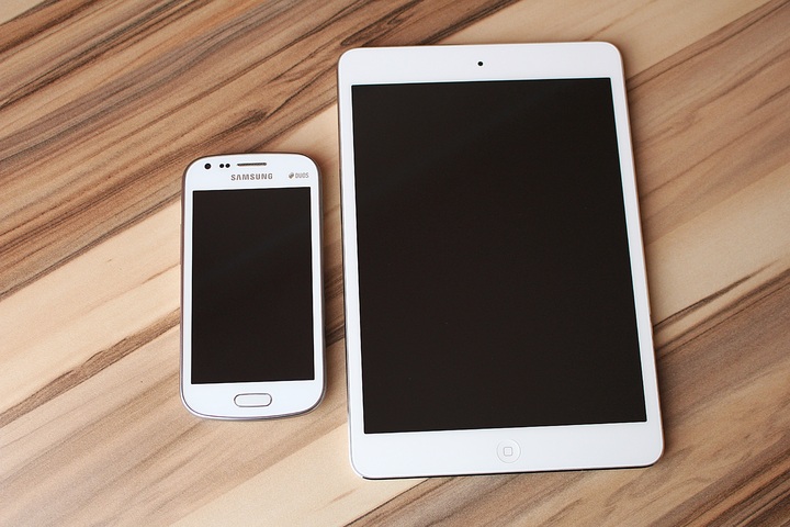 La imagen muestra un teléfono y una tableta sobre una mesa.