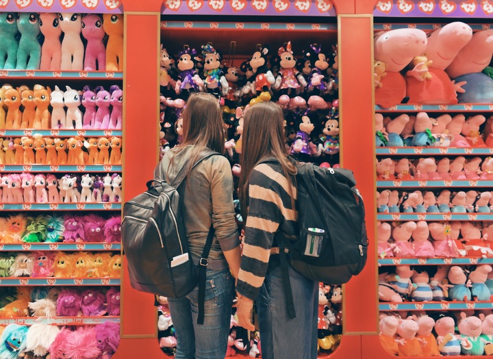 La imagen muestra a dos chicas en la puerta de una tienda llena de muñecos.