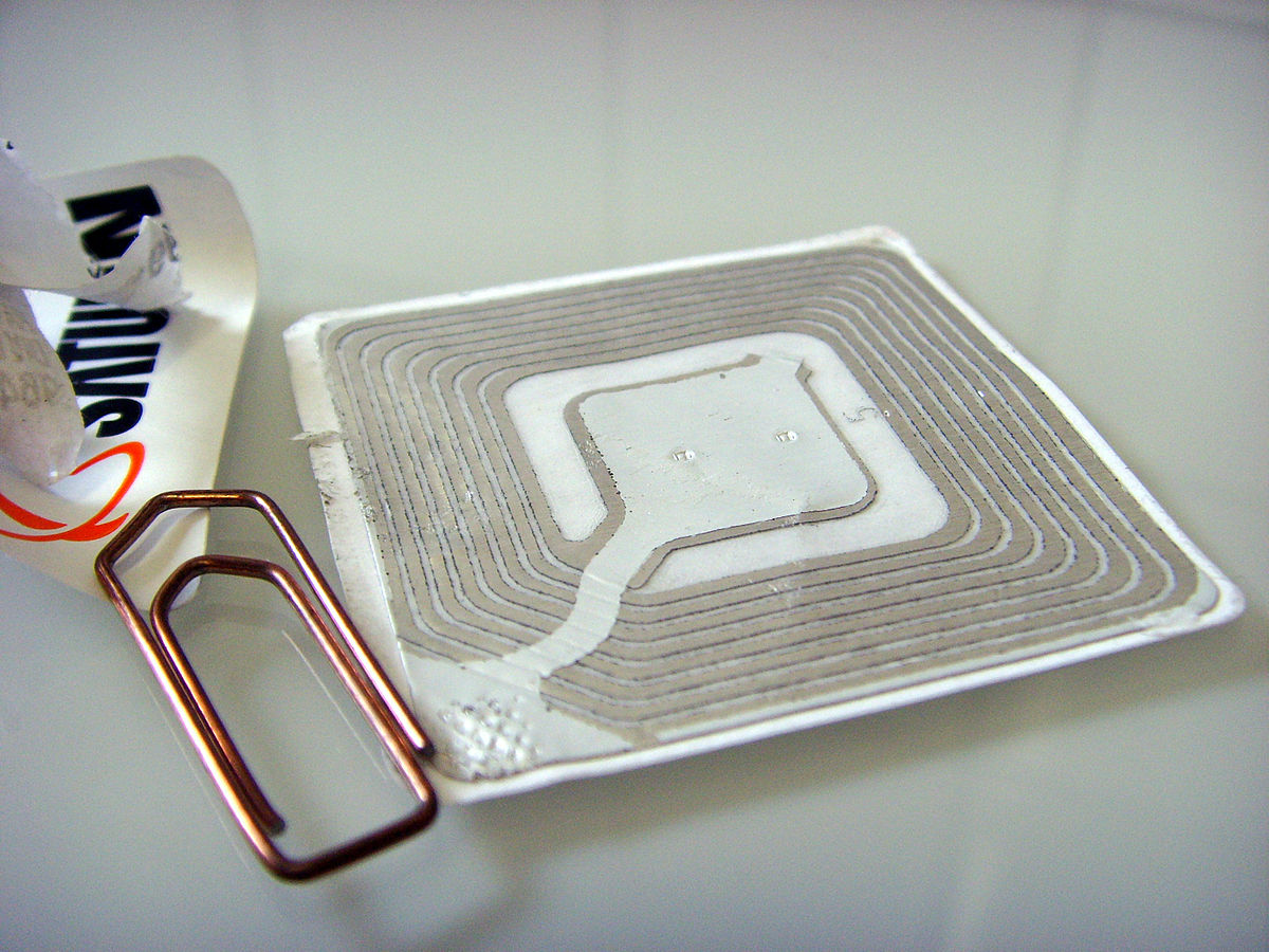 Imagen de una etiqueta RFID en comparación con un clip para ver su tamaño.