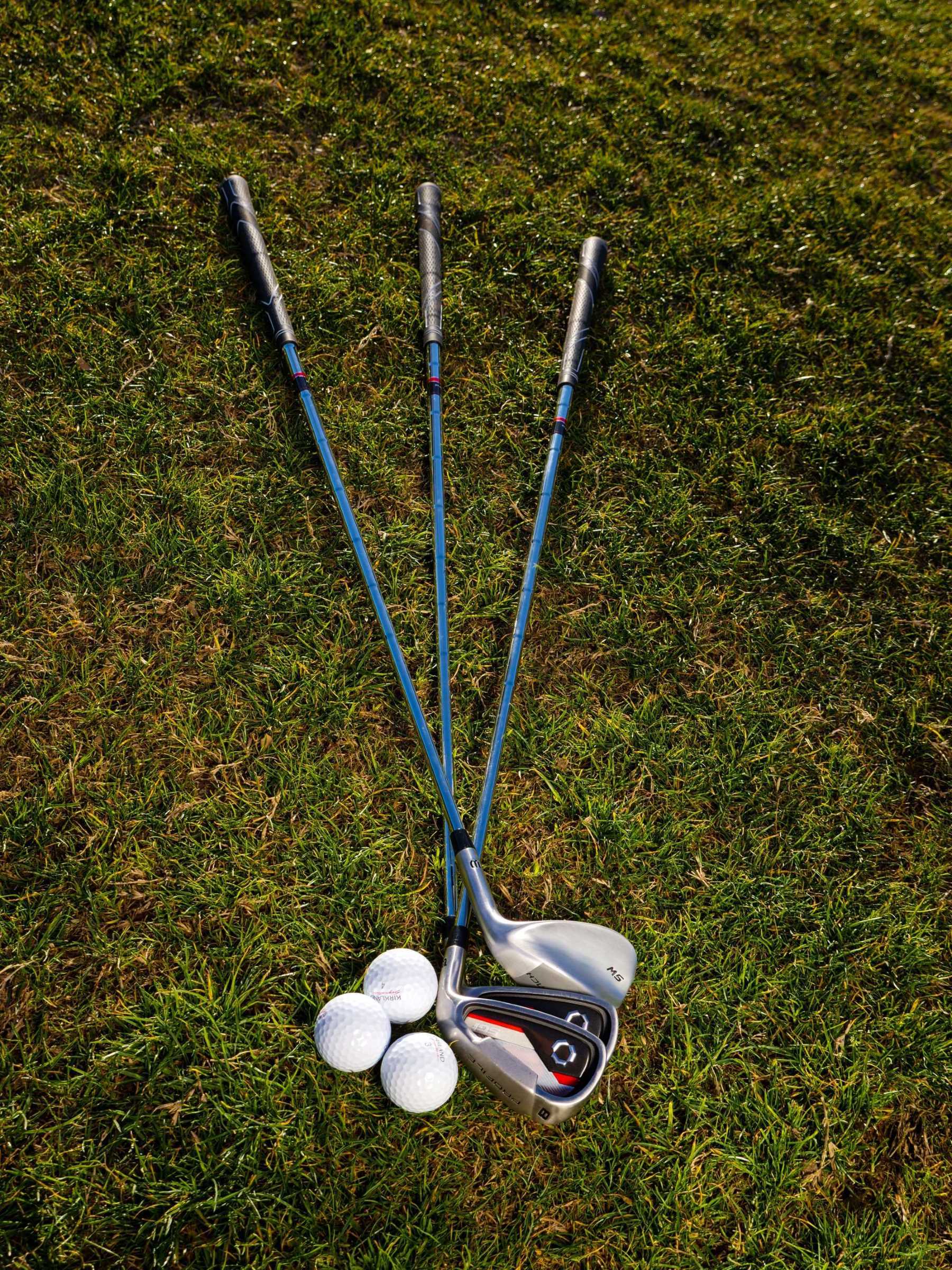 La imagen muestra unos palos de golf sobre el césped.