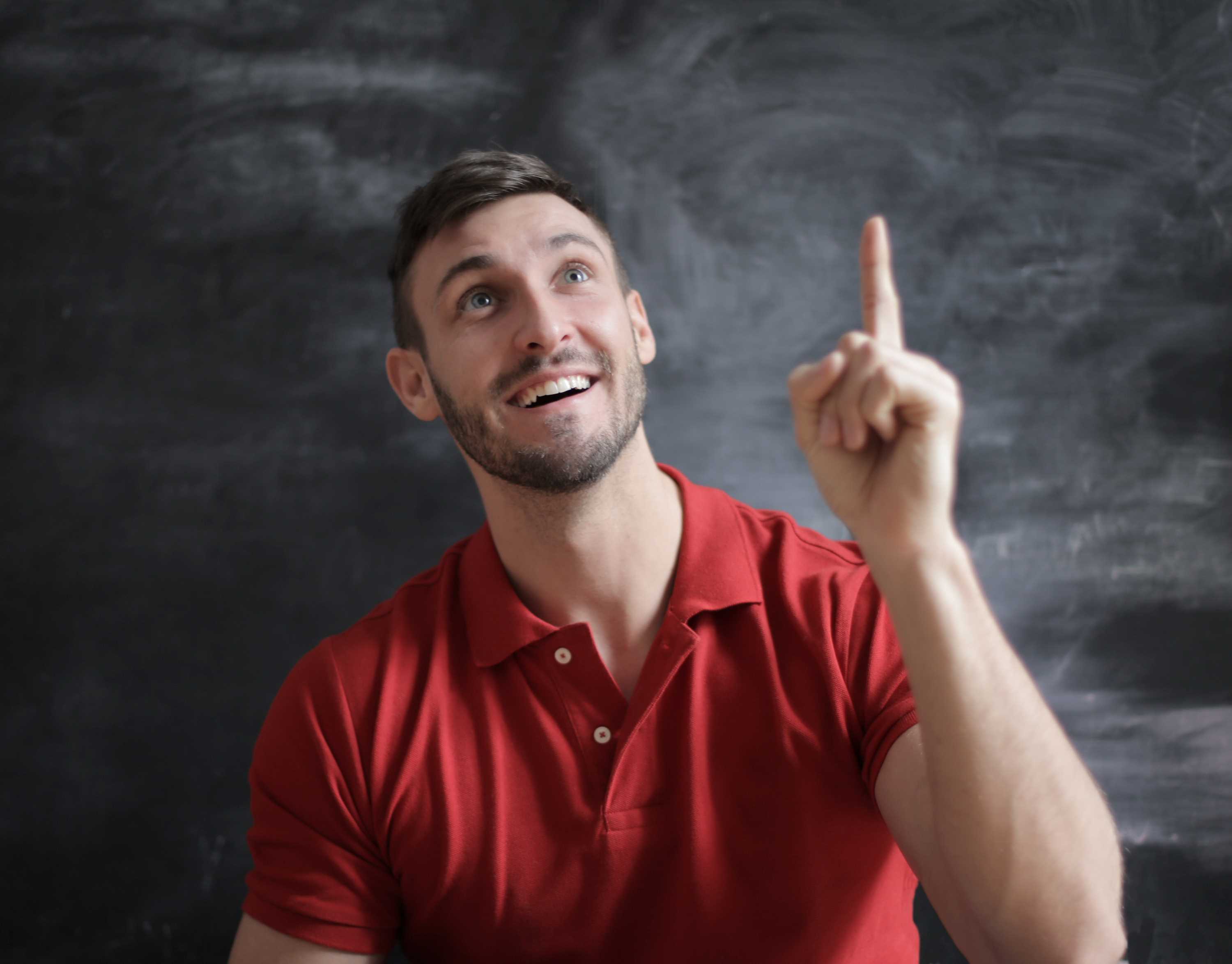 La imagen muestra una persona sonriendo mientras sube un dedo en un intento de hablar.