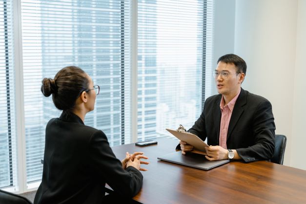 La imagen muestra a dos personas en un despacho mientras mantienen una entrevista. 