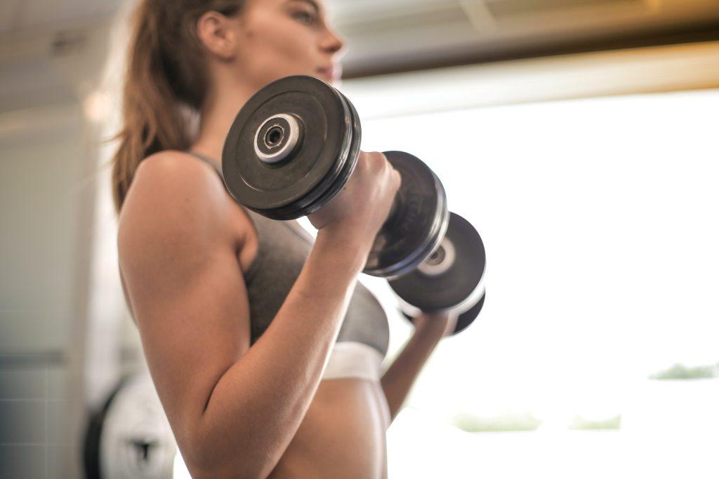 La imagen muestra una mujer haciendo ejercicio en el gimnasio.