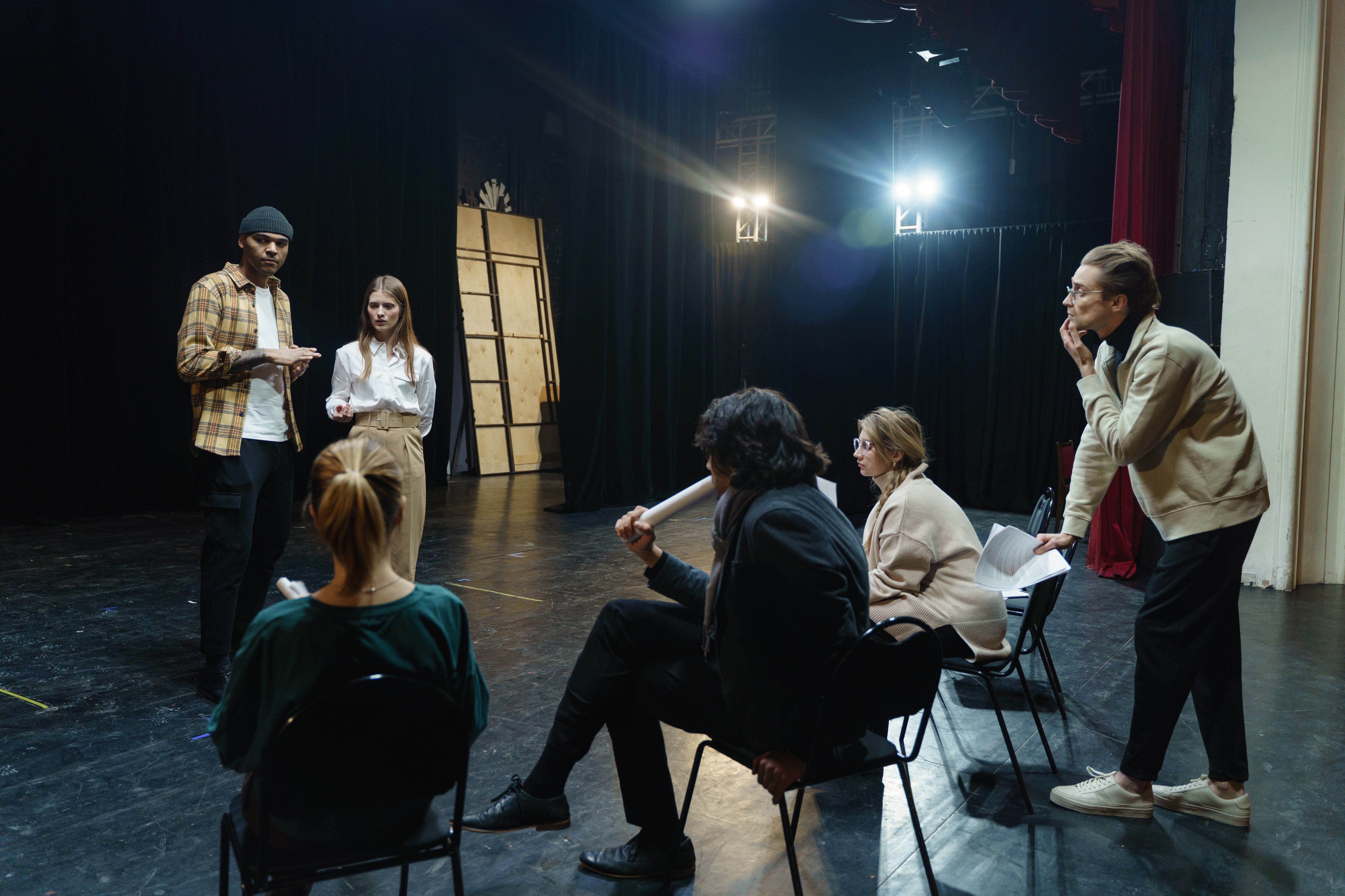 5 jóvenes en un escenario teatral ensayando una obra