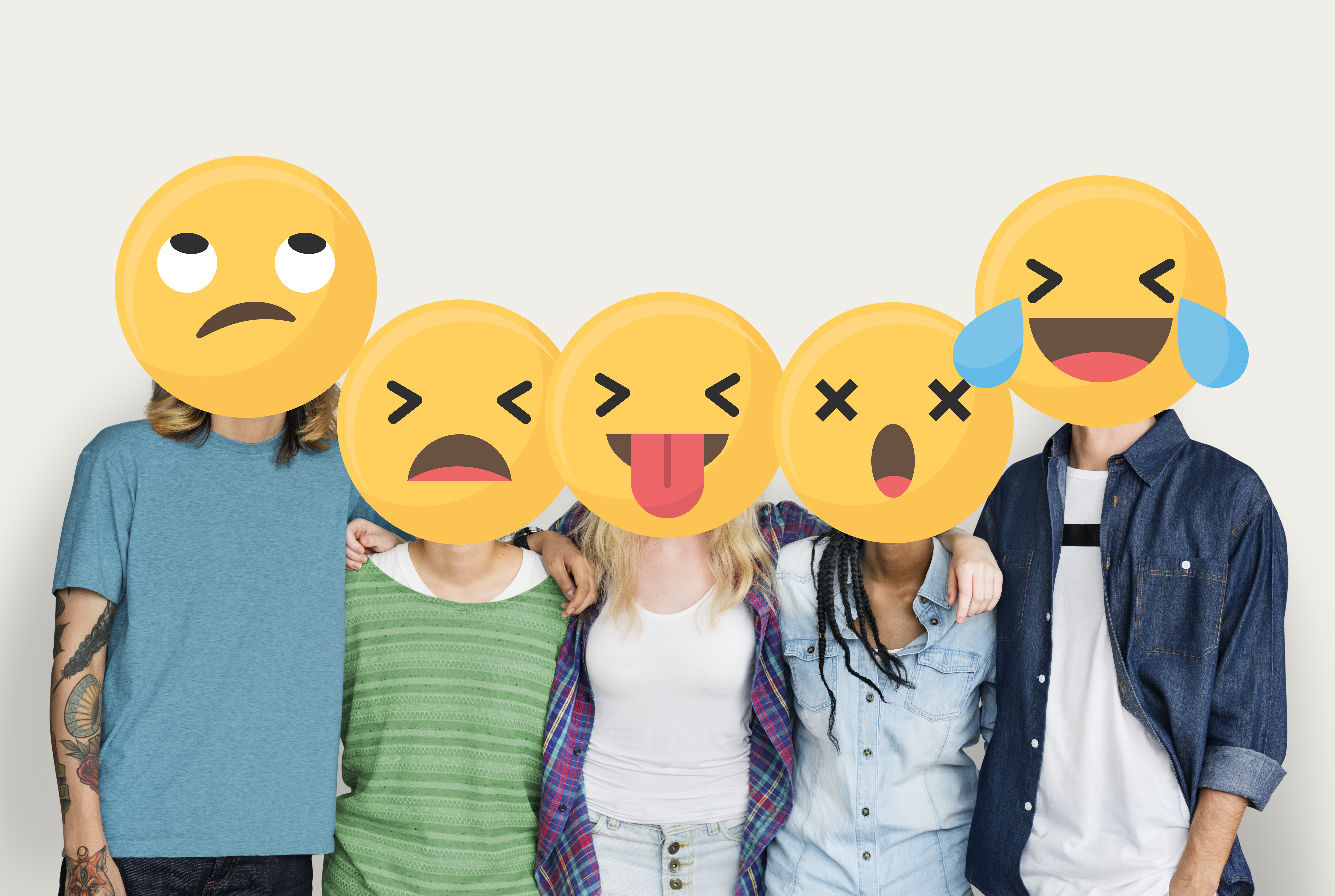 En la imagen se ve a un grupo de cinco personas cogidos unos de otros. Sus caras están tapadas por emojis con diferentes emociones