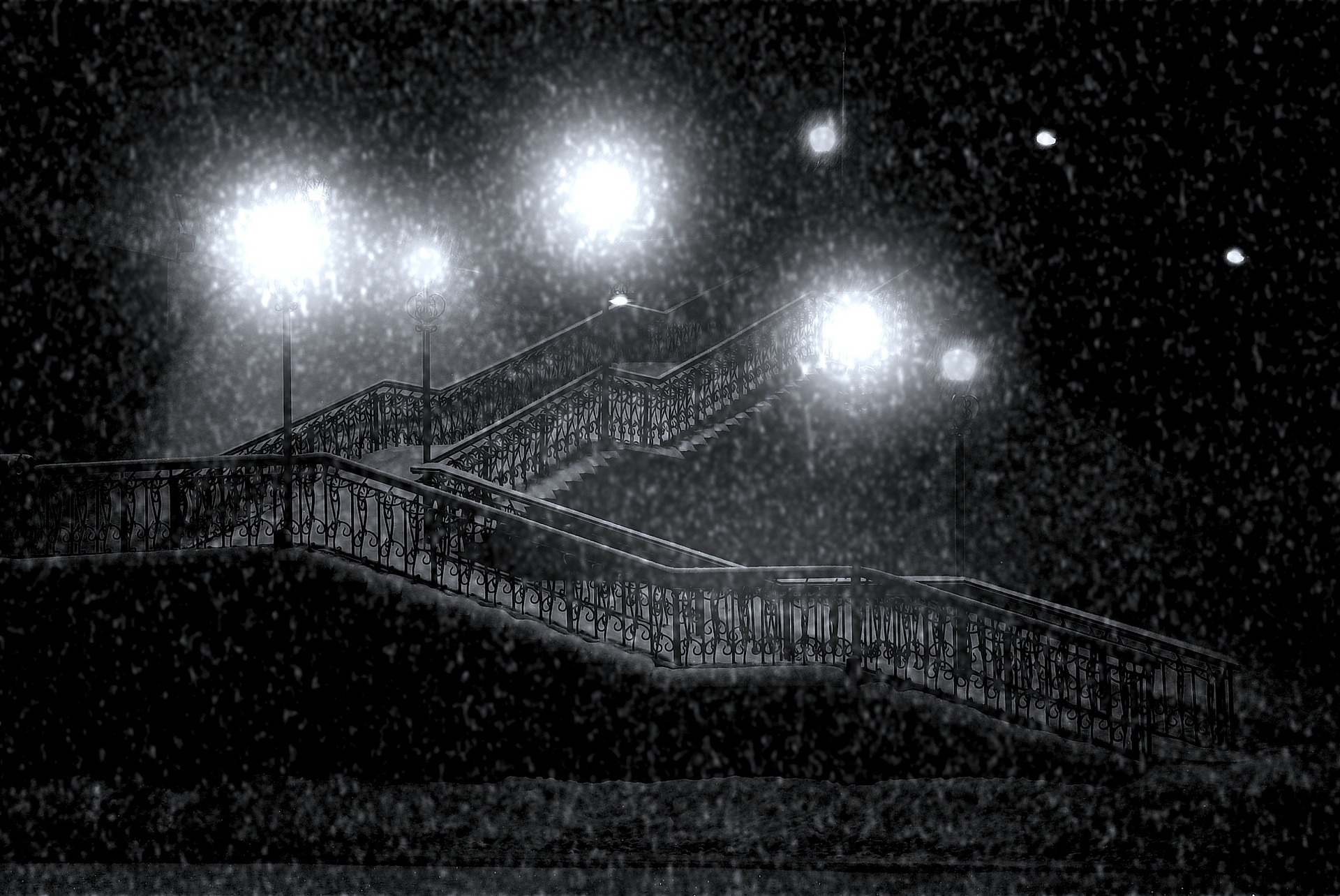 es una fotografía de una escalera muy larga en una noche en la que está nevando, y que está iluminada sólo por las farolas.