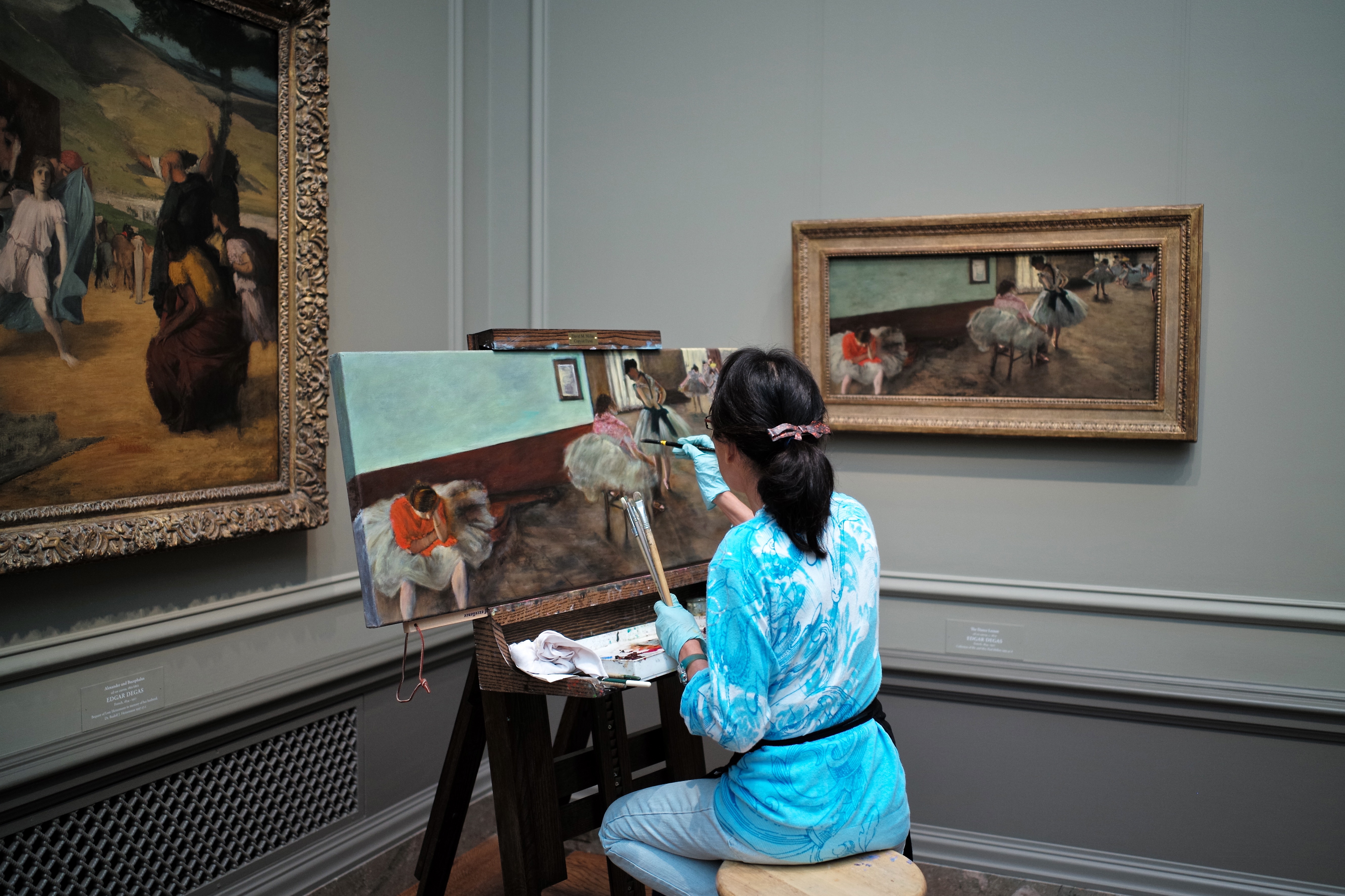 En la imagen aparece una mujer pintando un cuadro igual que otro cuadro que hay en la pared.