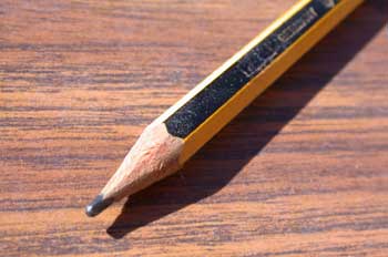La imagen muestra un lápiz negro, decorado con líneas amarillas y negras