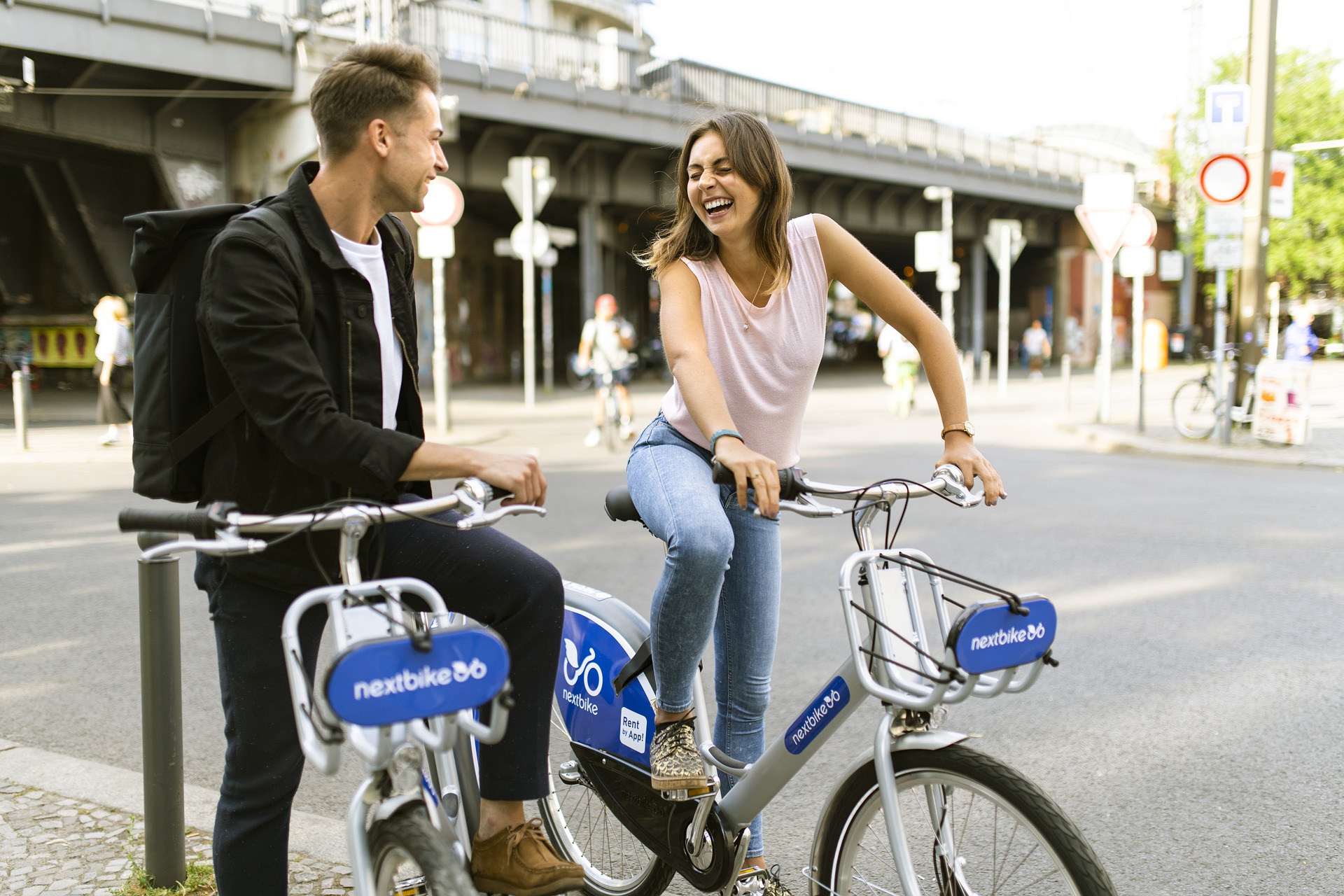 Un chico y una chica se ríen subidos en sendas bicis