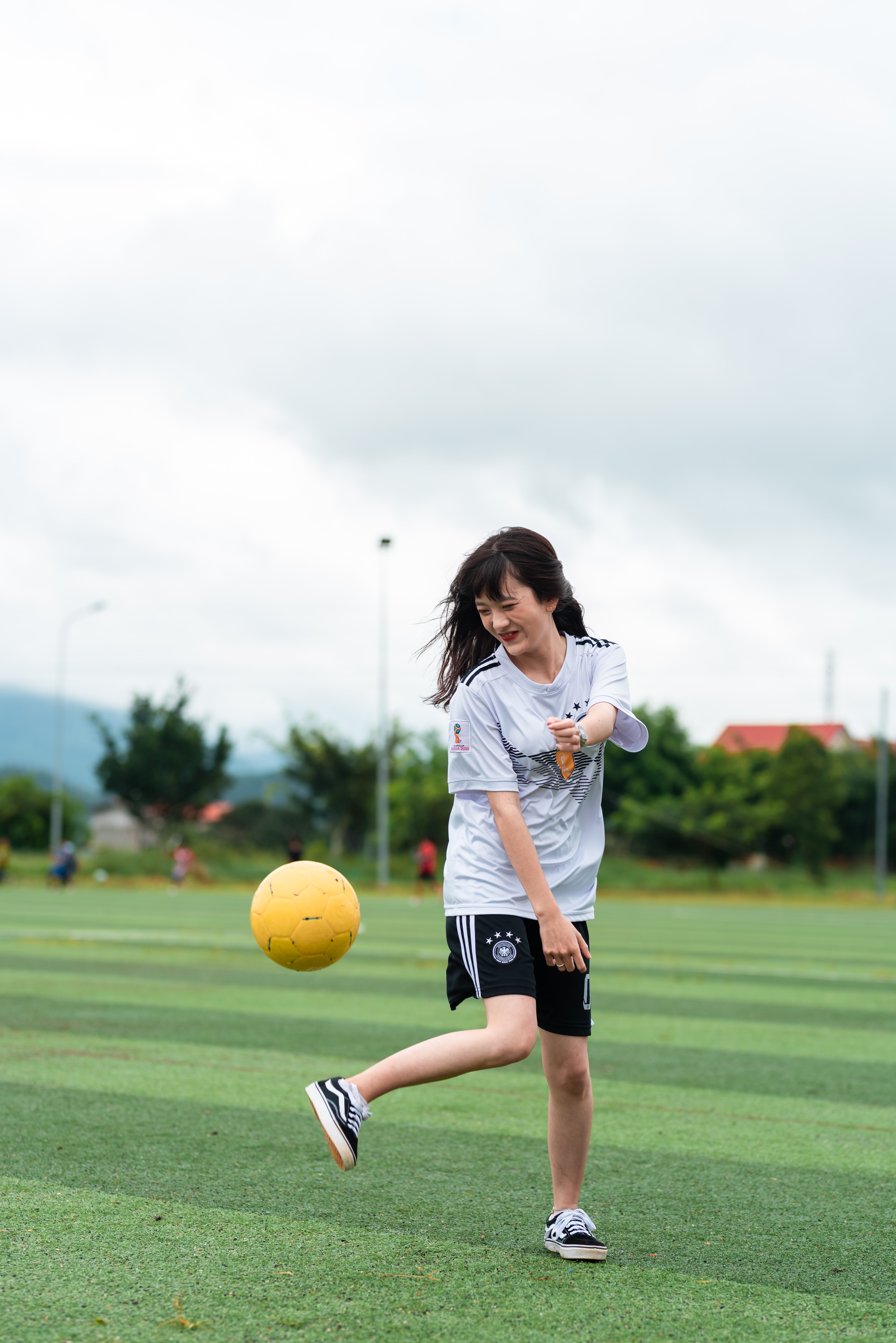 Chica pateando una pelota en un campo de fútbol