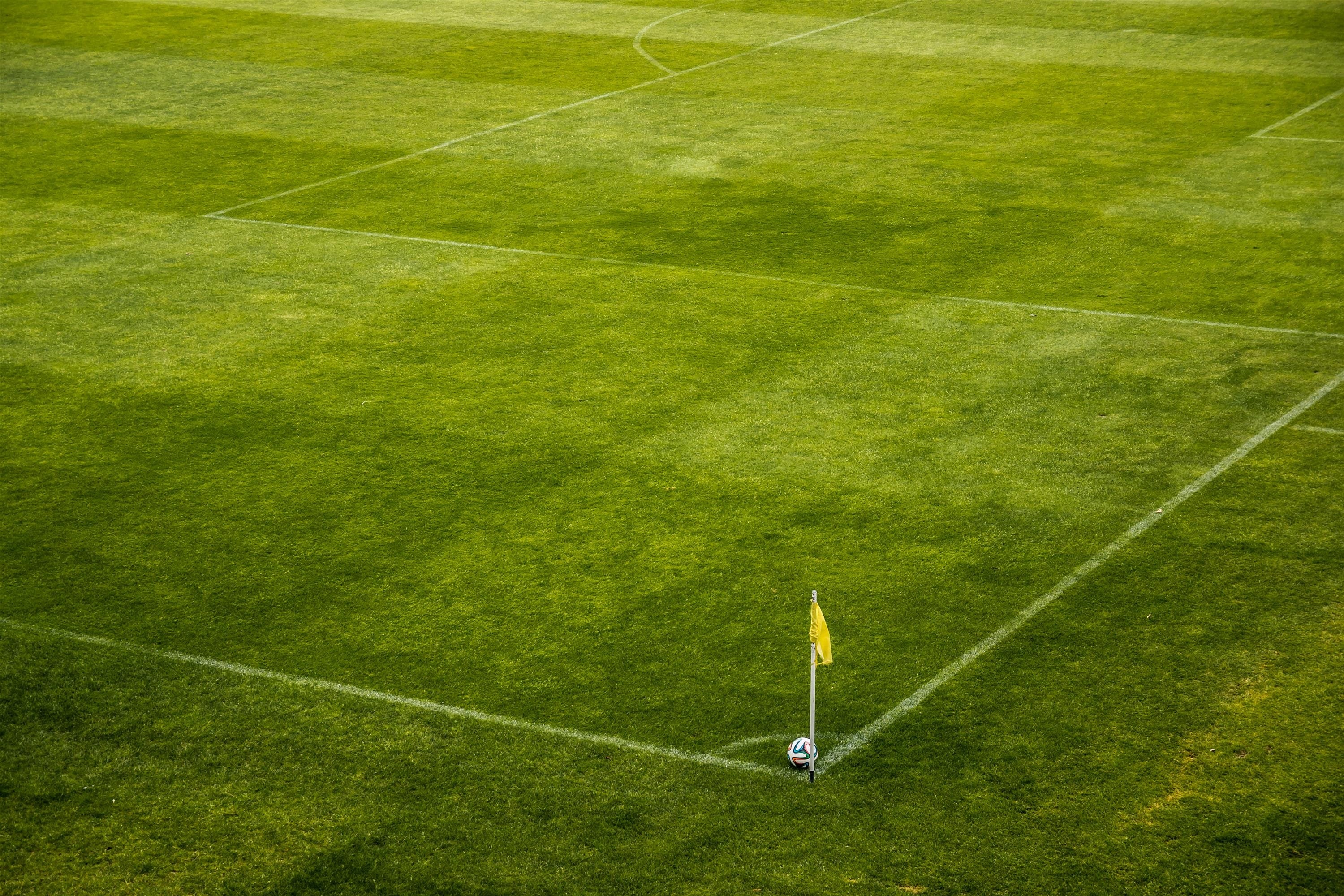 Aparece un el corner de un campo de fútbol con un banderín y una pelota en la esquina