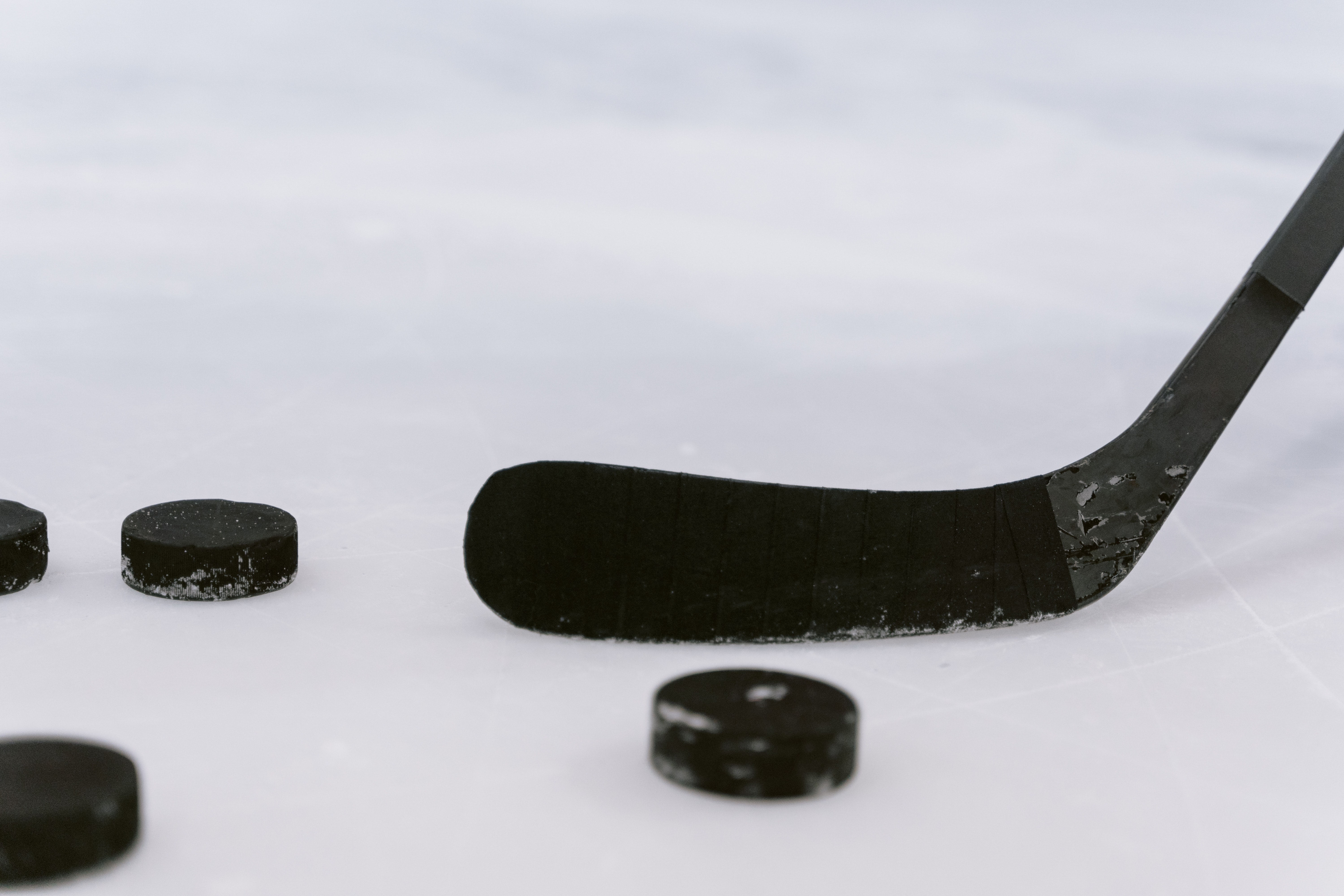 Palo de hockey sobre el hielo de una pista y varias pastillas de hockey