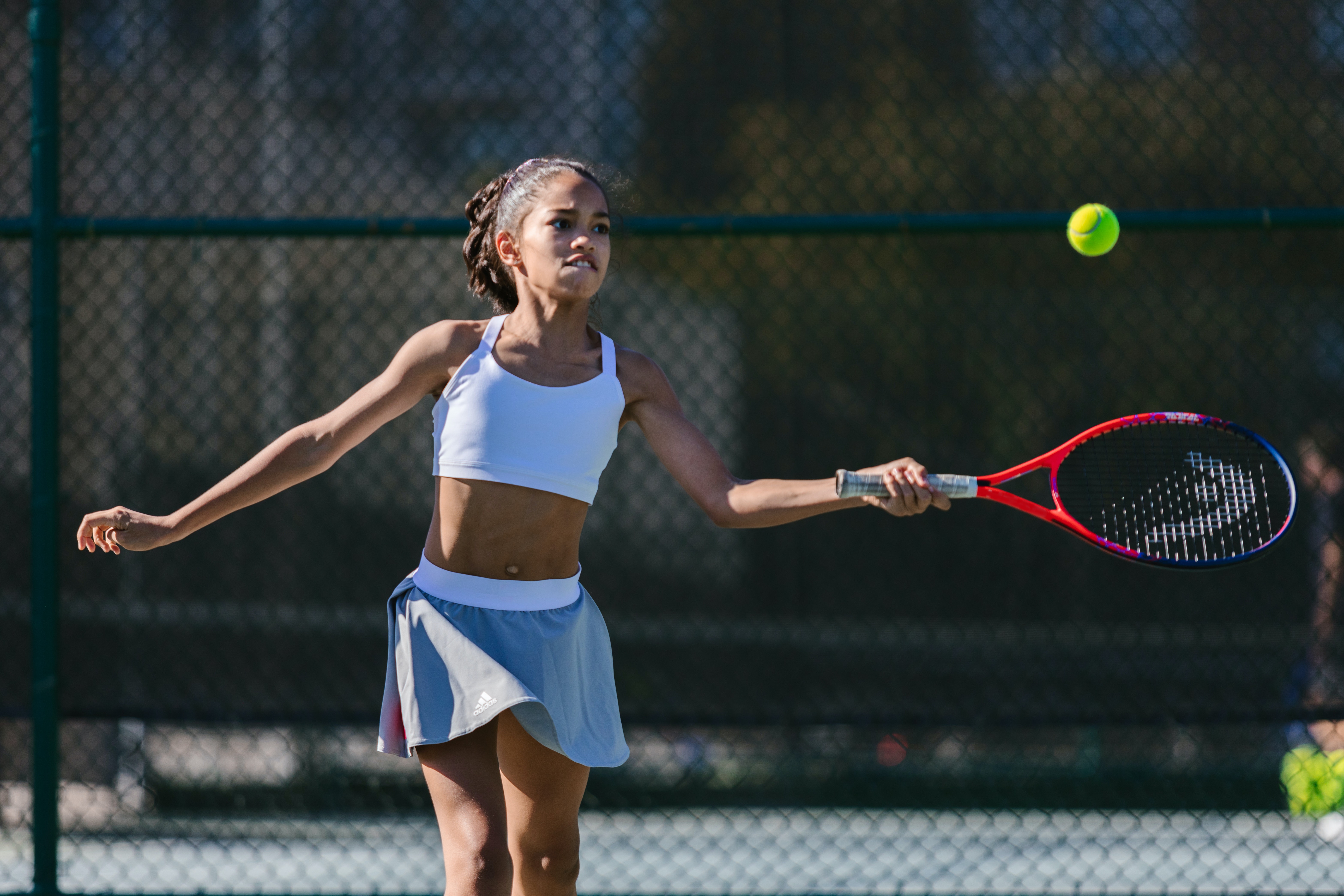 Chica golpeando una pelota de tenis con una raqueta.