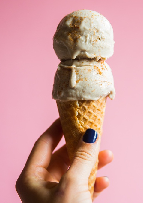 La imagen muestra un cono de helado con dos bolas de helado cogido por una mano