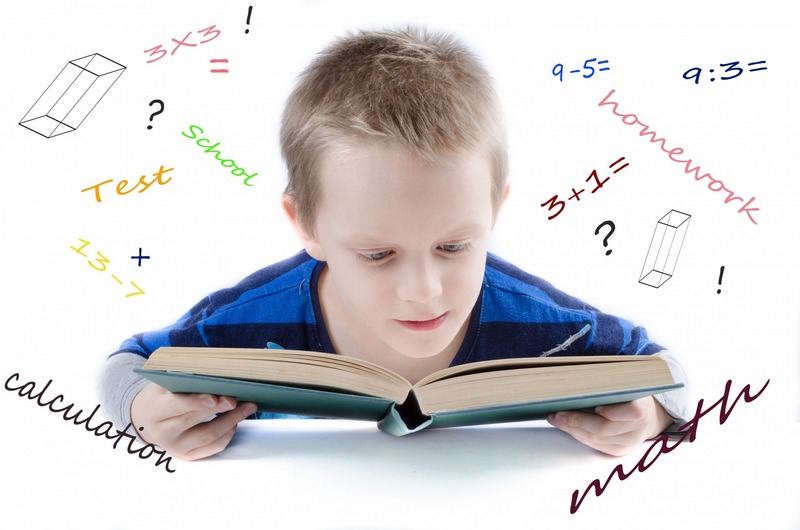 La imagen muestra un niño con un libro delante y alrededor cuentas, dibujos y conceptos matemáticos