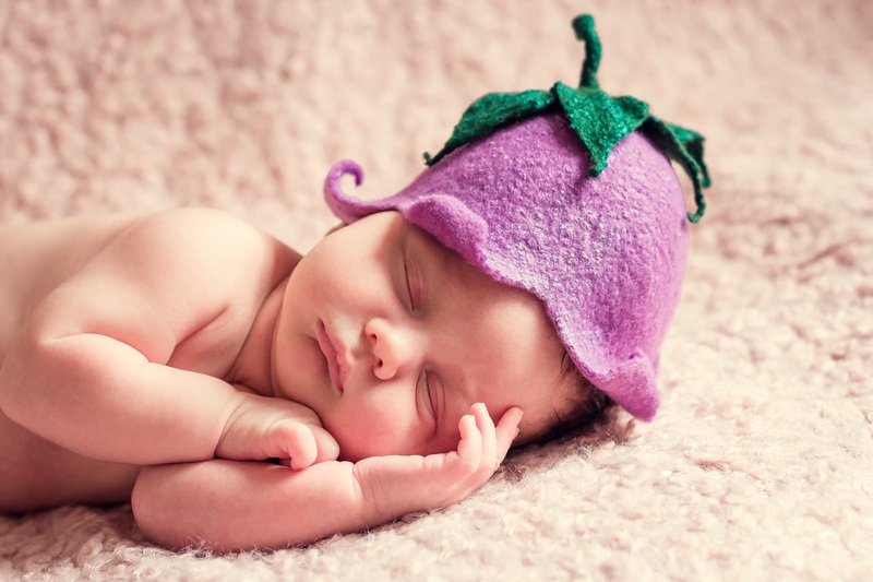 la imagen muestra  un bebé durmiendo con un gorro morado