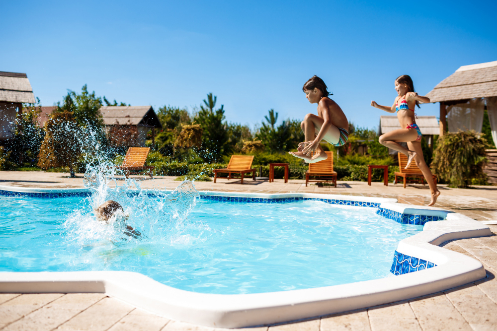 Niños alegres regocijándose, saltando, nadando en la piscina.