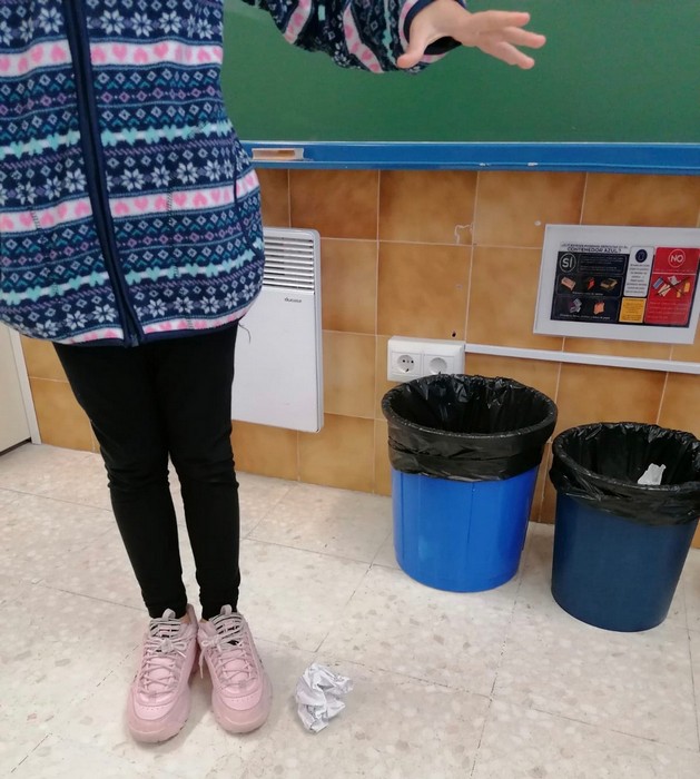 Una niña tirando un papel al suelo.