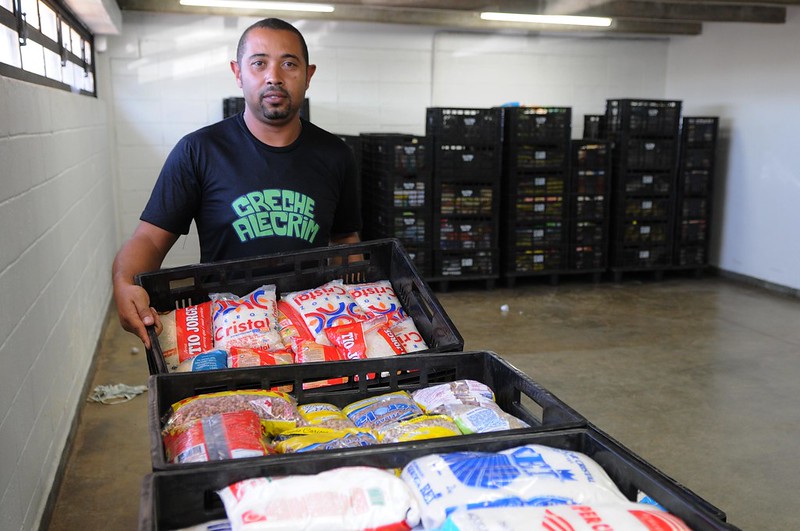 La imagen muestra a un voluntario de un banco de alimentos mostrando paquetes de comida en varias cestas.