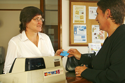 La imagen muestra una señora frente a una dependienta y una caja registradora.