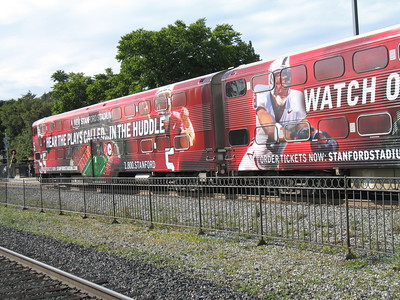 La imagen muestra un tren en cuyos vagones se anuncia un partido de fútbol americano.