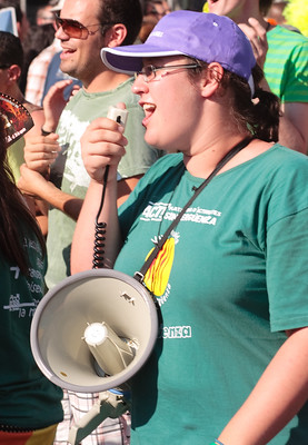 La imagen muestra a una joven que habla a un megáfono durante una manifestación.