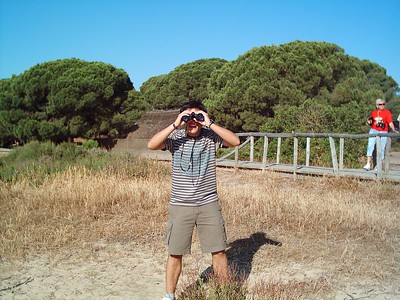 La imagen muestra a un joven que mira a través de unos prismáticos.
