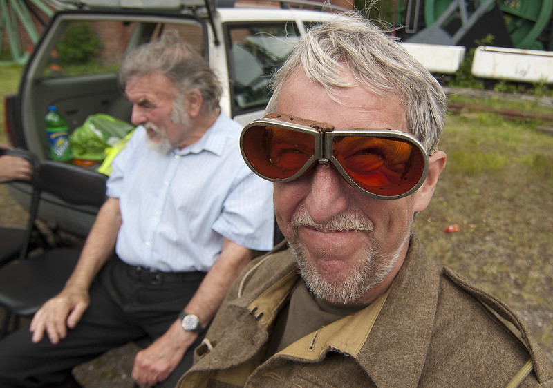 La imagen muestra a un señor mayor con unas antiguas gafas de conducir de cristal rojo. 