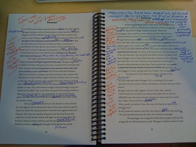 La imagen muestra una texto impreso con numerosas correcciones a mano en colores rojo y azul.
