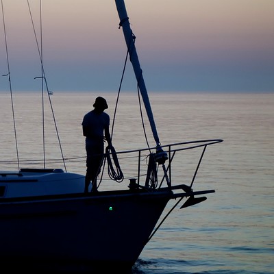 La imagen muestra la silueta de un marinero sobre la quilla de una embarcación.