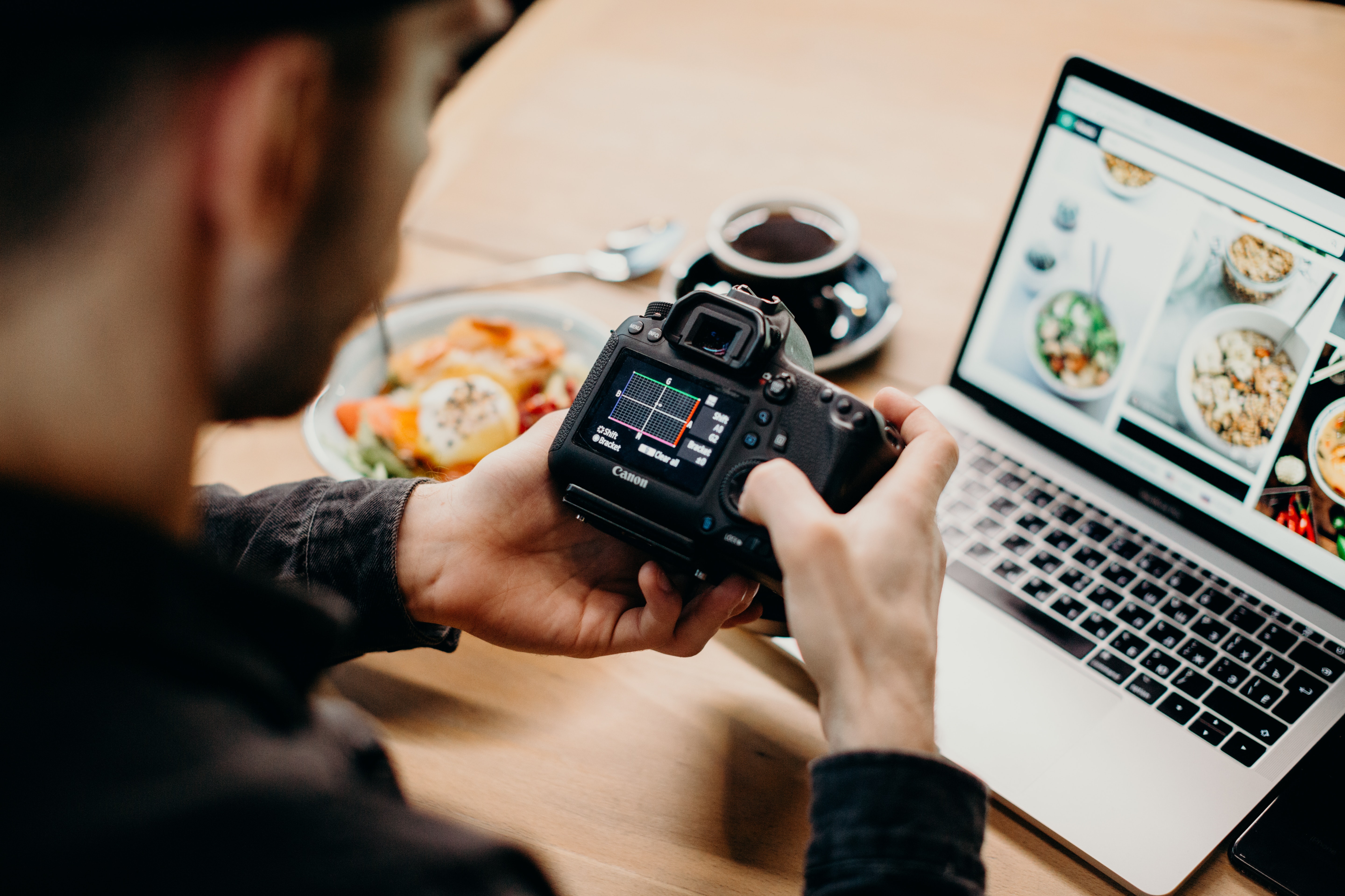 La imagen muestra un hombre pasando fotos de comida a un portátil