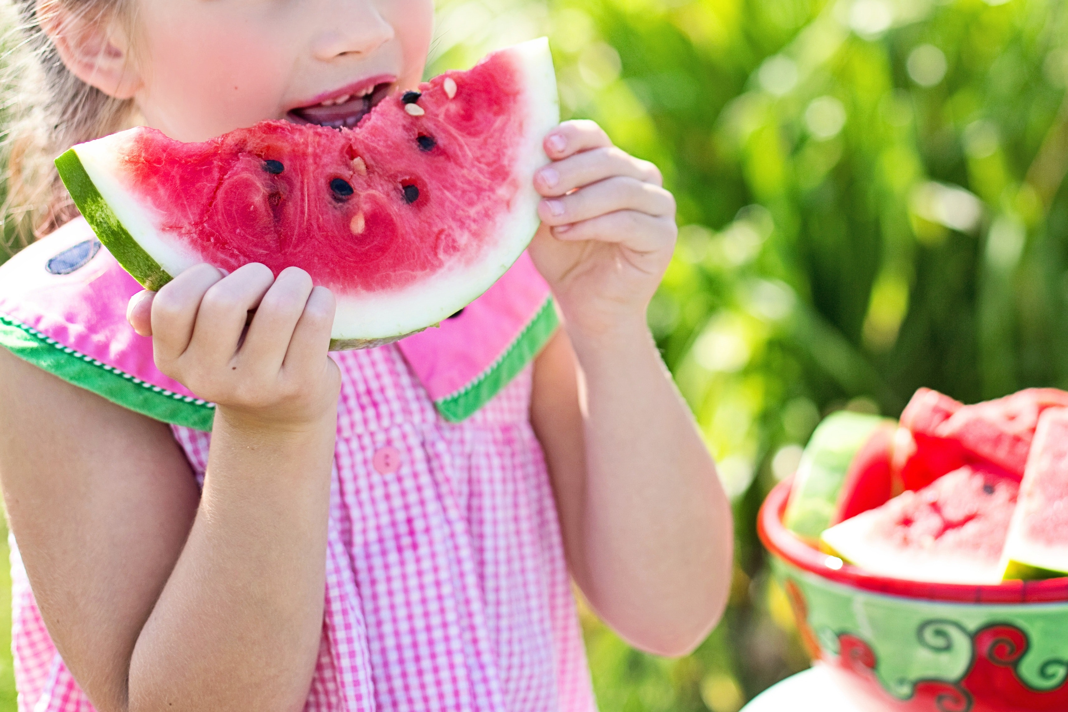 La imagen muestra una niña comiendo sandía.