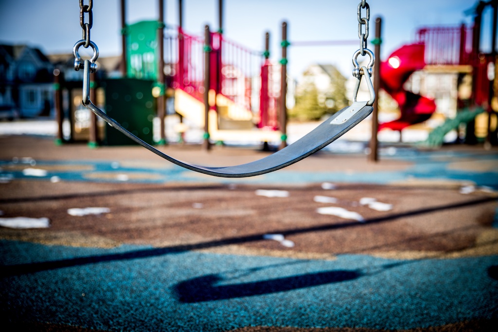 fotografía de un columpio dentro de un parque infantil con más elementos de juegos