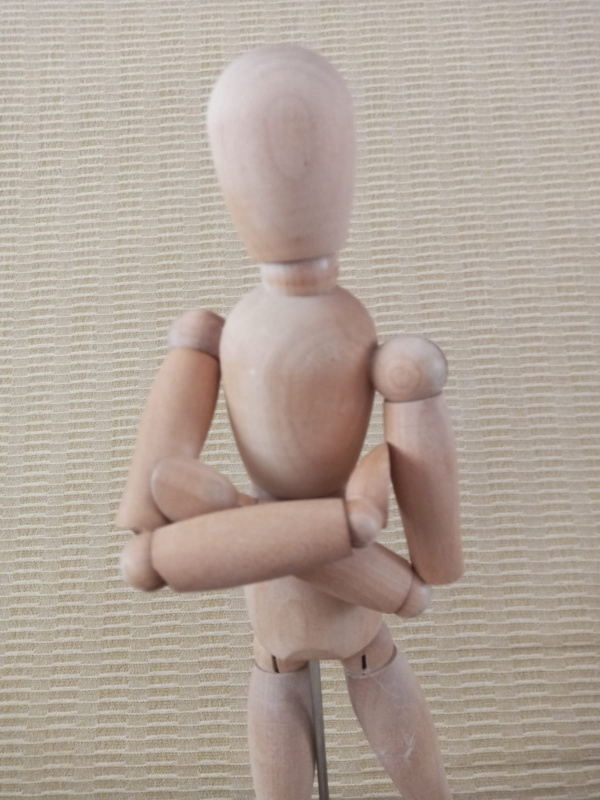 La imagen muestra una figura articulada con los brazos cruzados