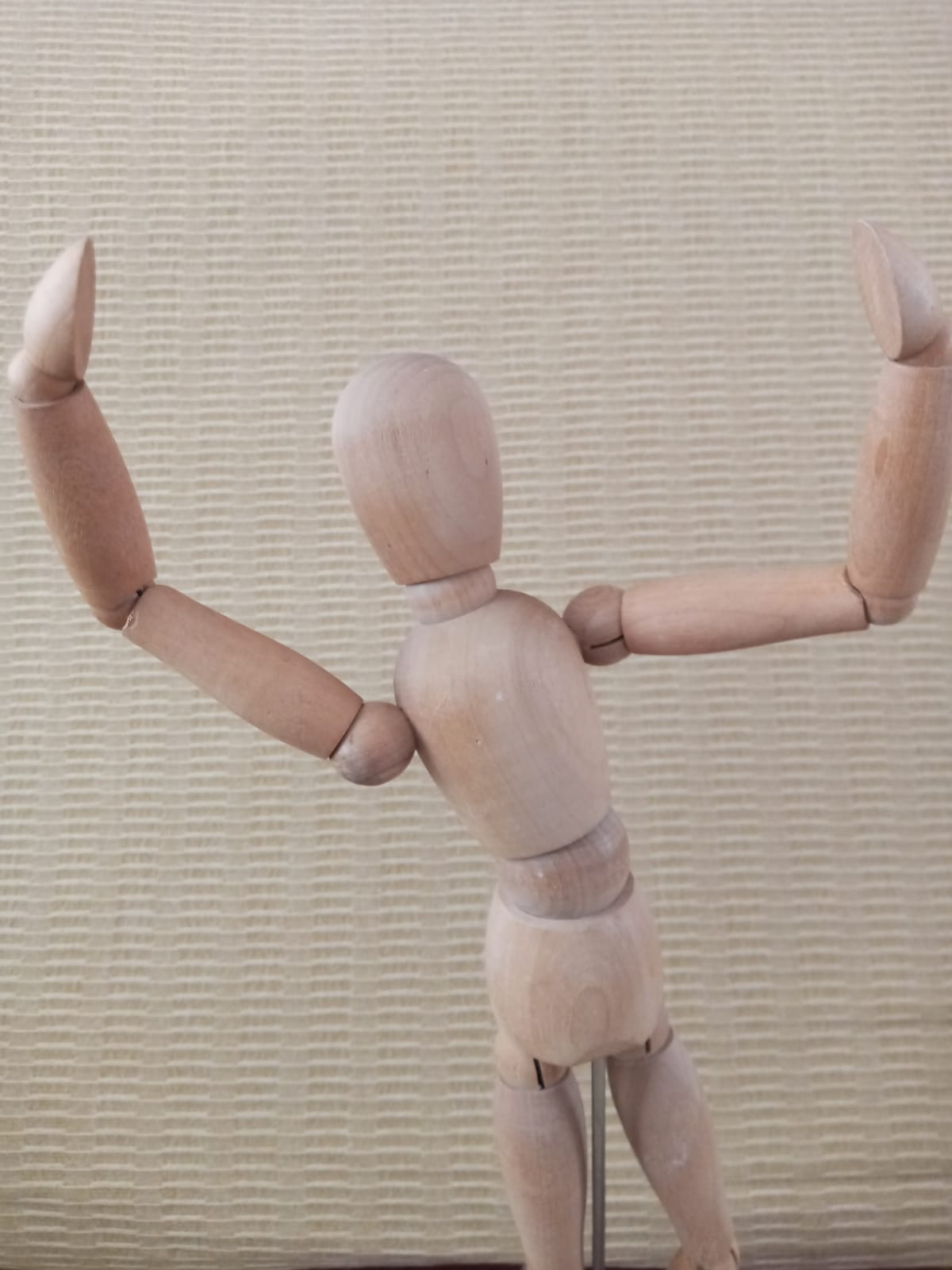 La imagen muestra una figura articulada con los brazos abiertos en alto