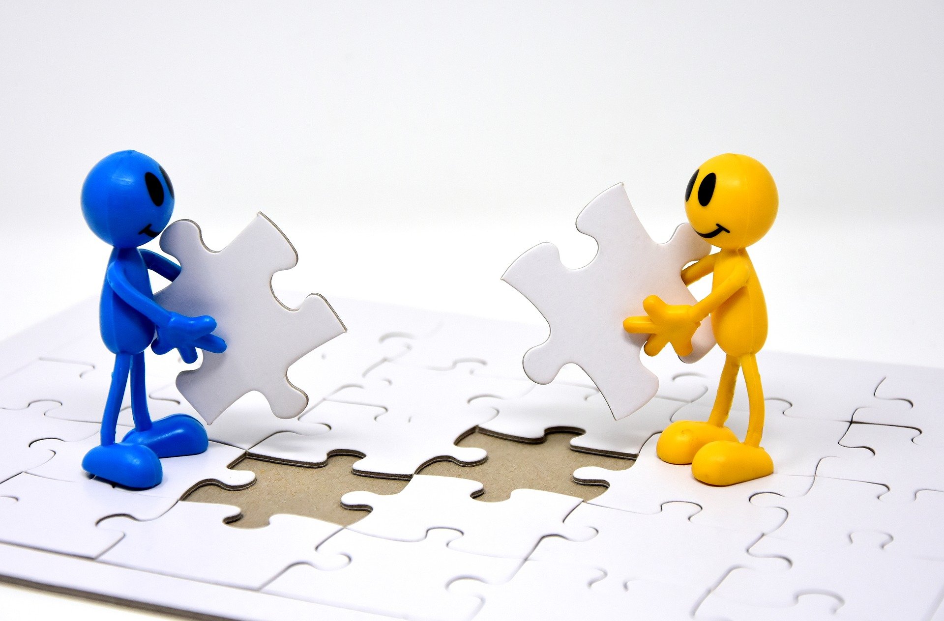 La imagen muestra un muñeco azul y un muñeco amarillo, que están de pie sobre un puzzle al que faltan las dos piezas que ellos sostienen en las manos