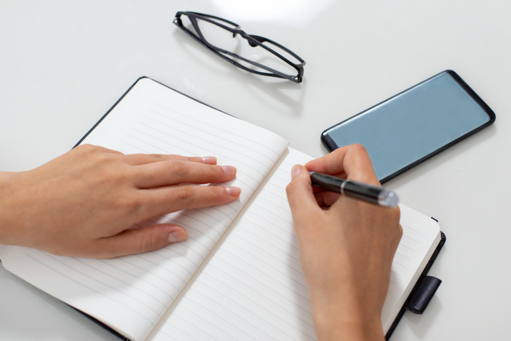 La imagen muestra una persona empezando a escribir en un cuaderno