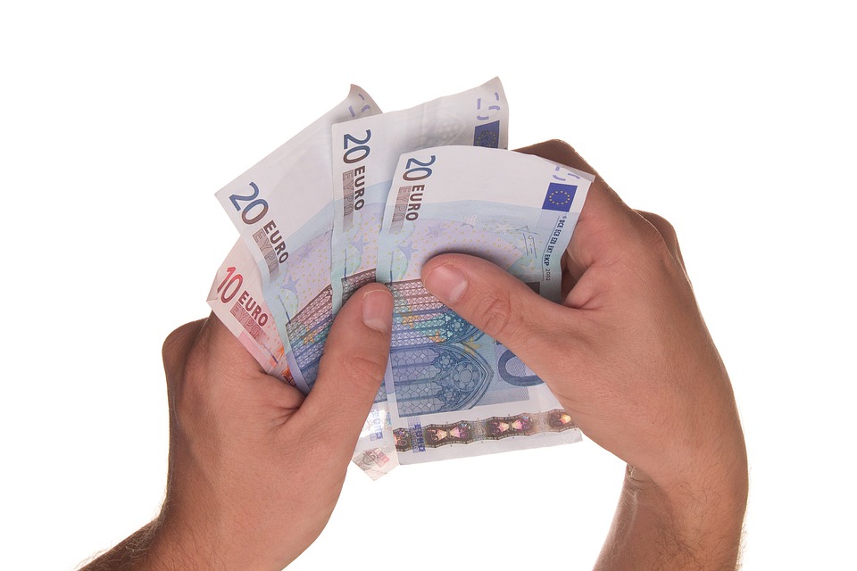La imagen muestra unas manos sosteniendo varios billetes