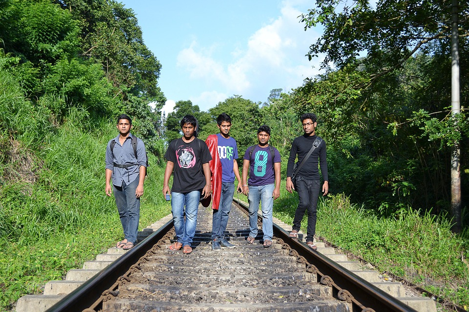 La imagen muestra cinco chicos morenos caminando por la via de un tren