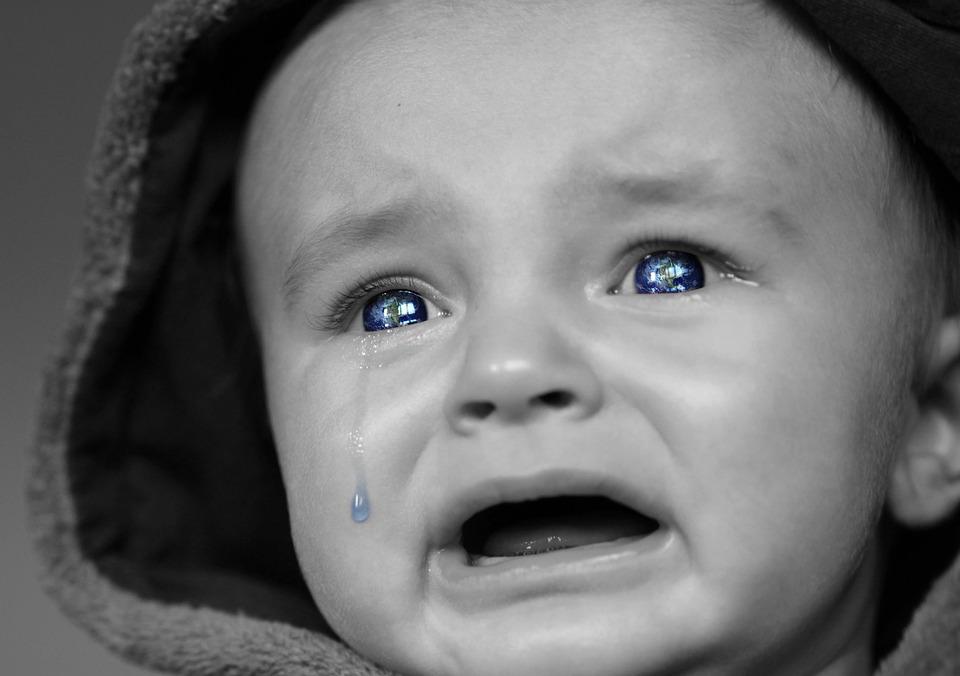 La imagen muestra un bebé con lagrimas en los ojos