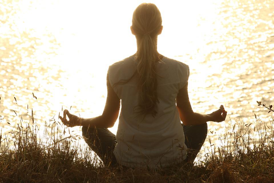 La imagen muestra una mujer practicando meditación
