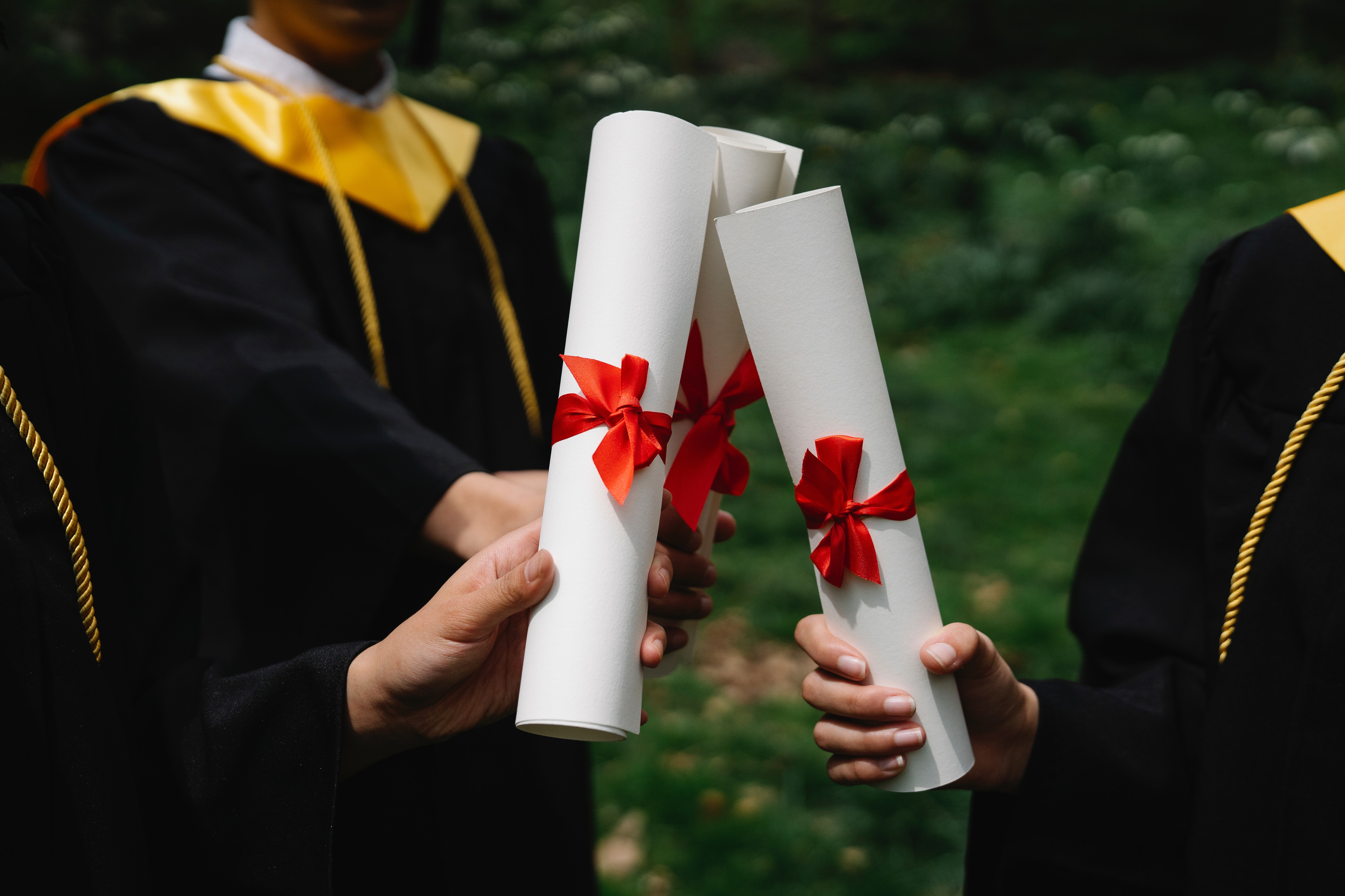 La imagen muestra a unos recién graduados mostrando sus diplomas.
