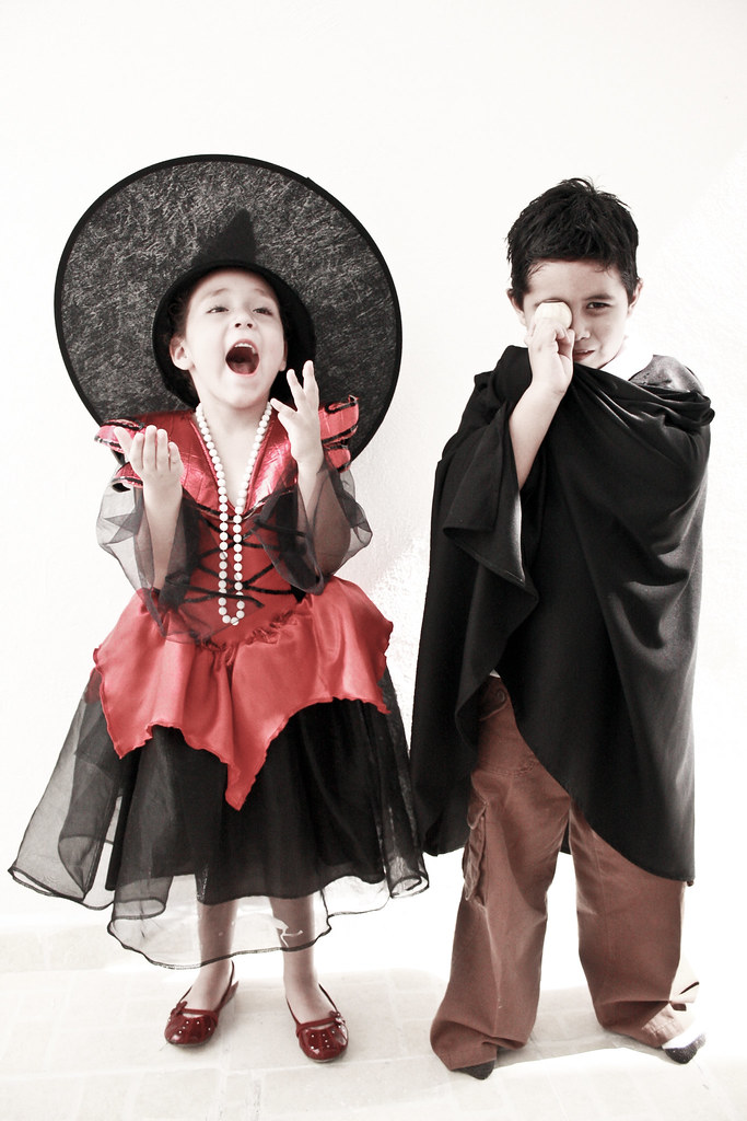 La imagen muestra una niña disfrazada de bruja y un niño de drácula