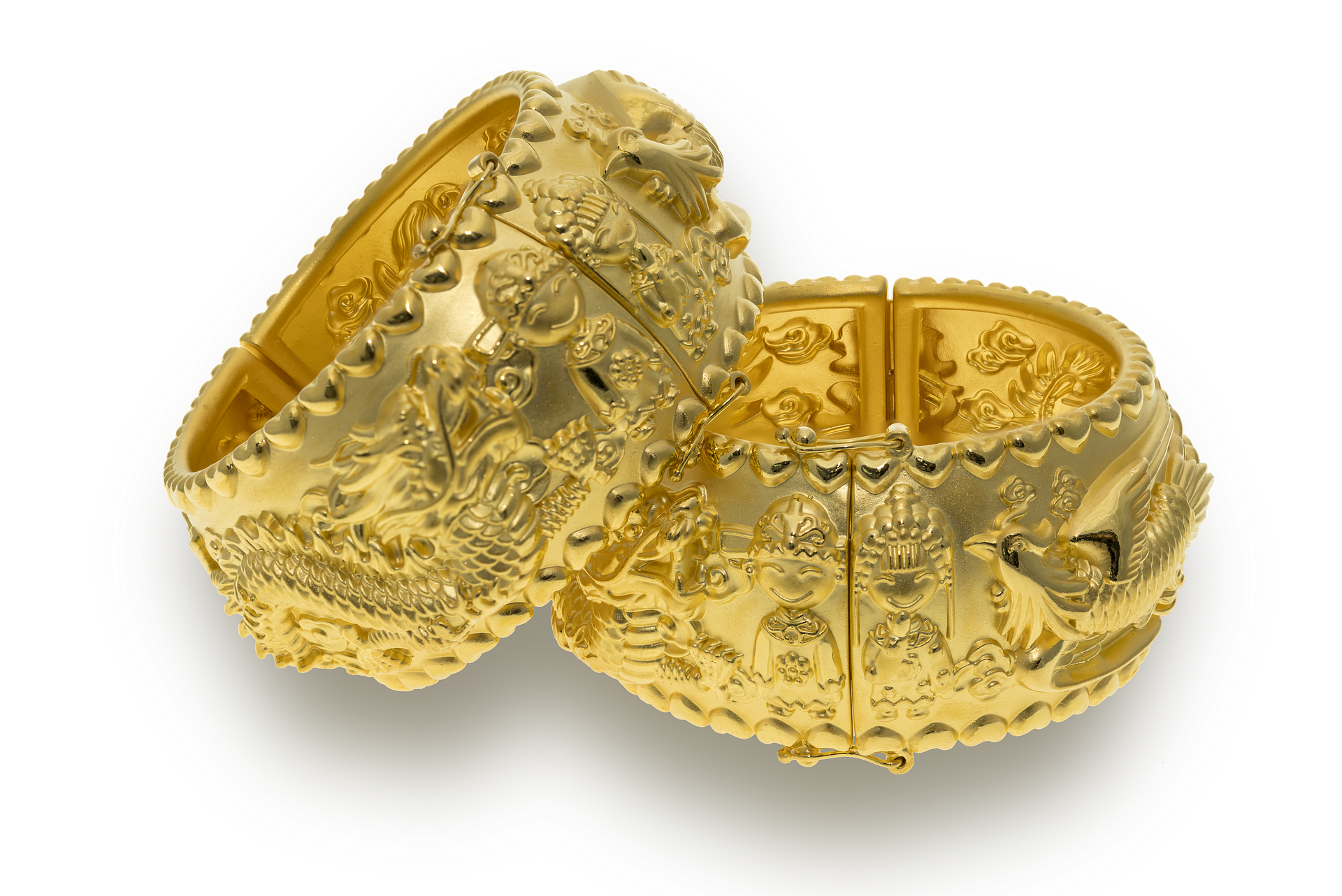 La imagen muestra dos brazaletes dorados con dibujos y cenefas en relieve