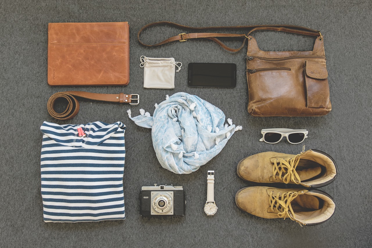 La imagen muestra una fotografía en la que hay distintos complementos de vestir, como gafas, bolso, pañuelo, cinturón, reloj, etc