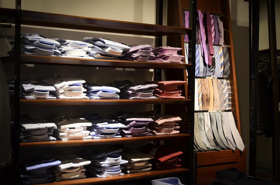 La imagen muestra el interior de una tienda en la que hay un estante con camisas y otro con corbatas