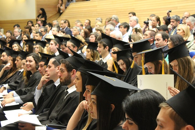 Imagen general de la ceremonia de una graduación con estudiantes vestidos con birretes y togas sentados entre el público.
