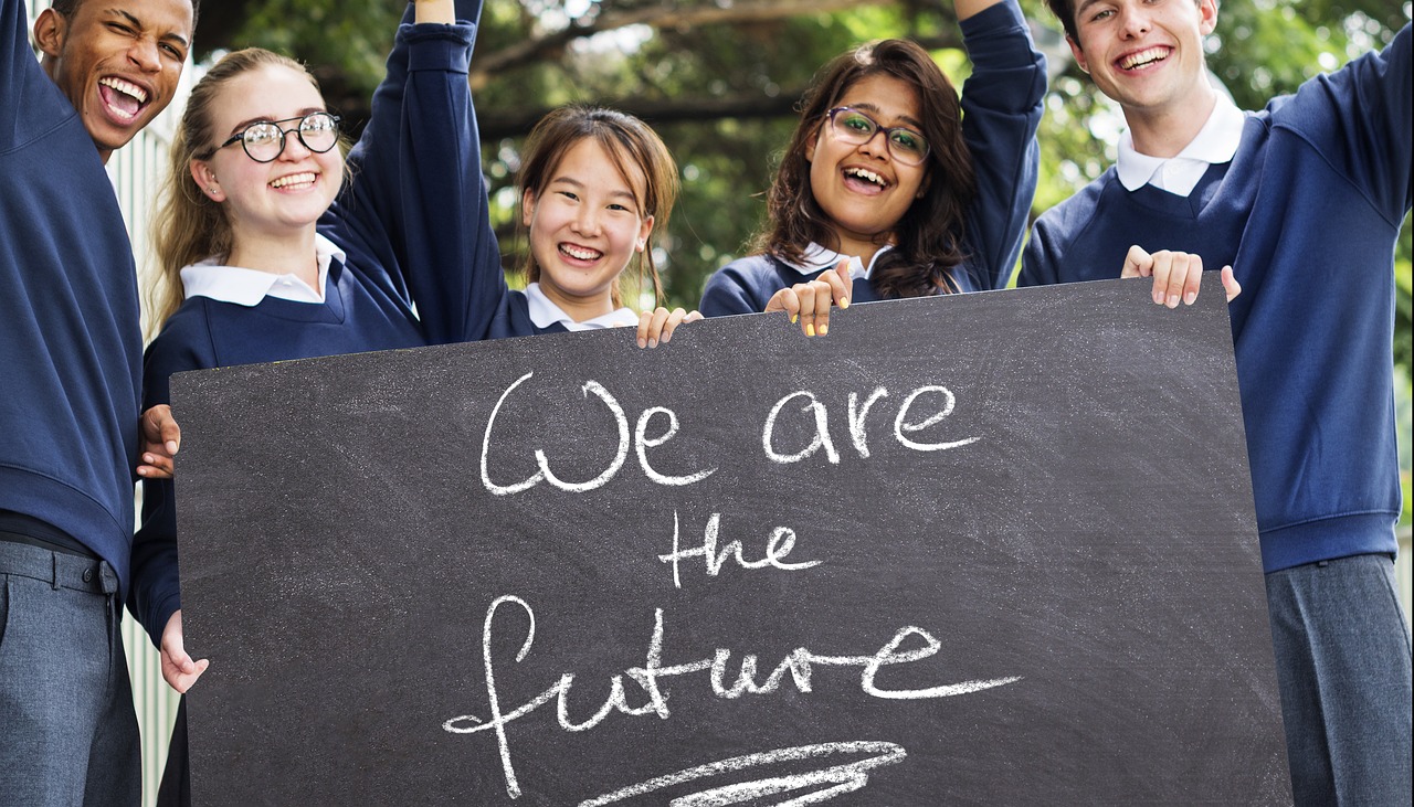 Cinco estudiantes sostienen un cartel que indica “We are the future”