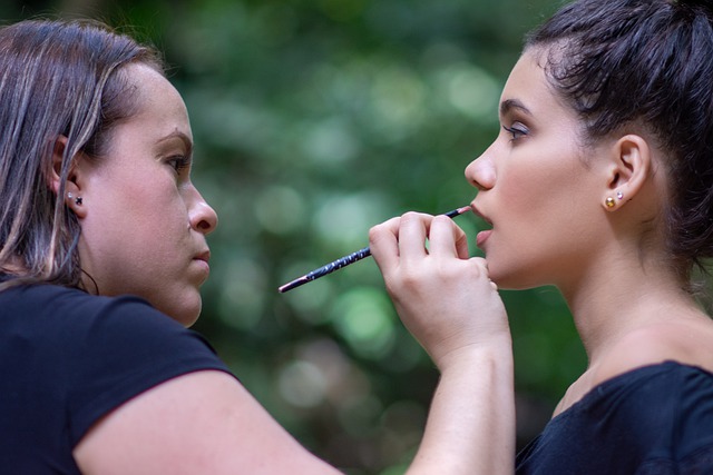 mujer maquillando a otra mujer los labios.