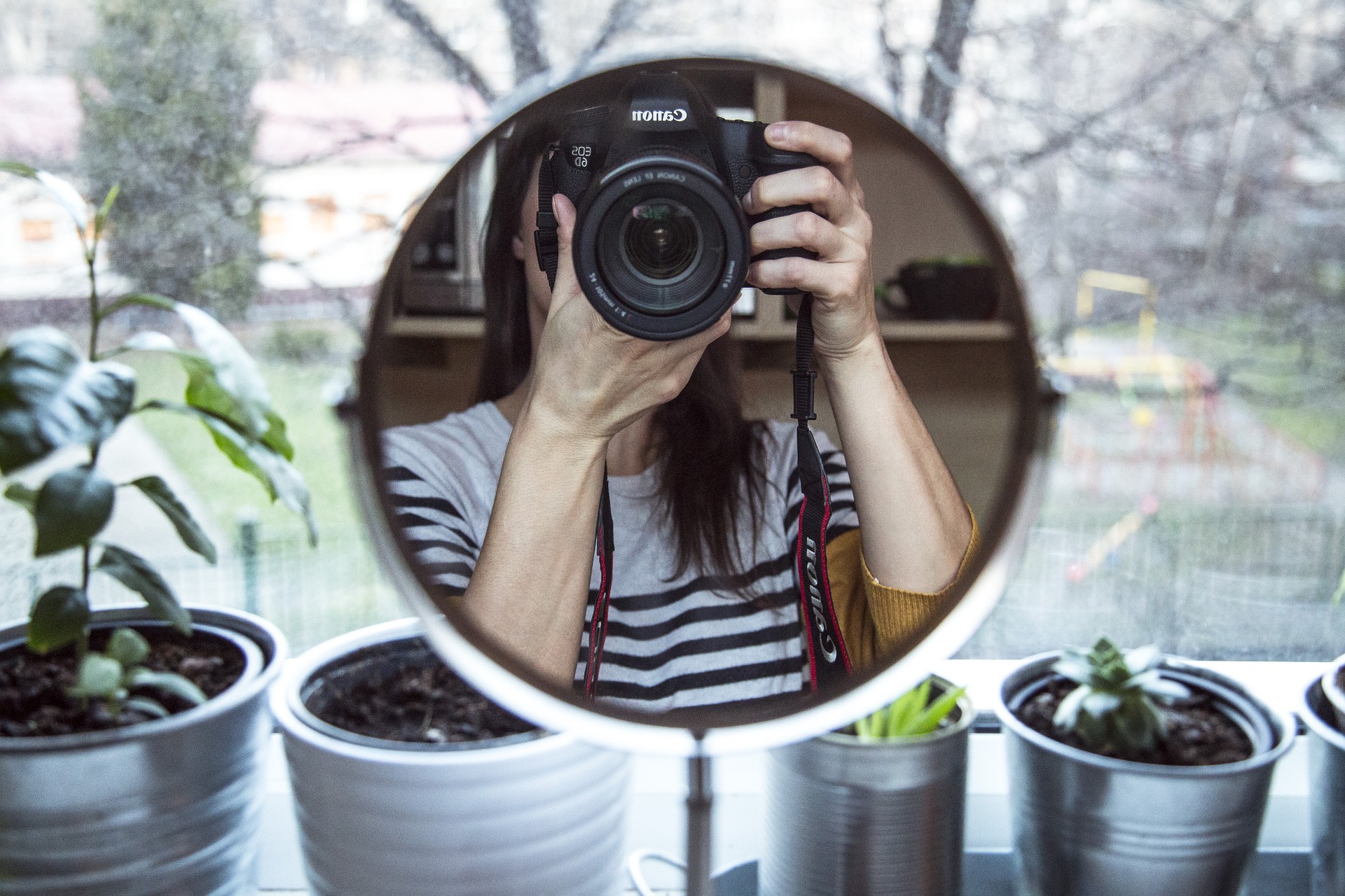 Reflejo en un espejo de una chica fotografiándose con su cámara réflex